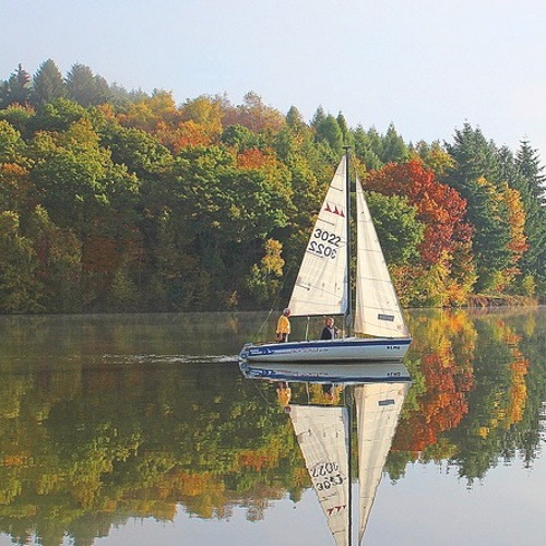 Sailboat with two people on board sailing with full sails being flown